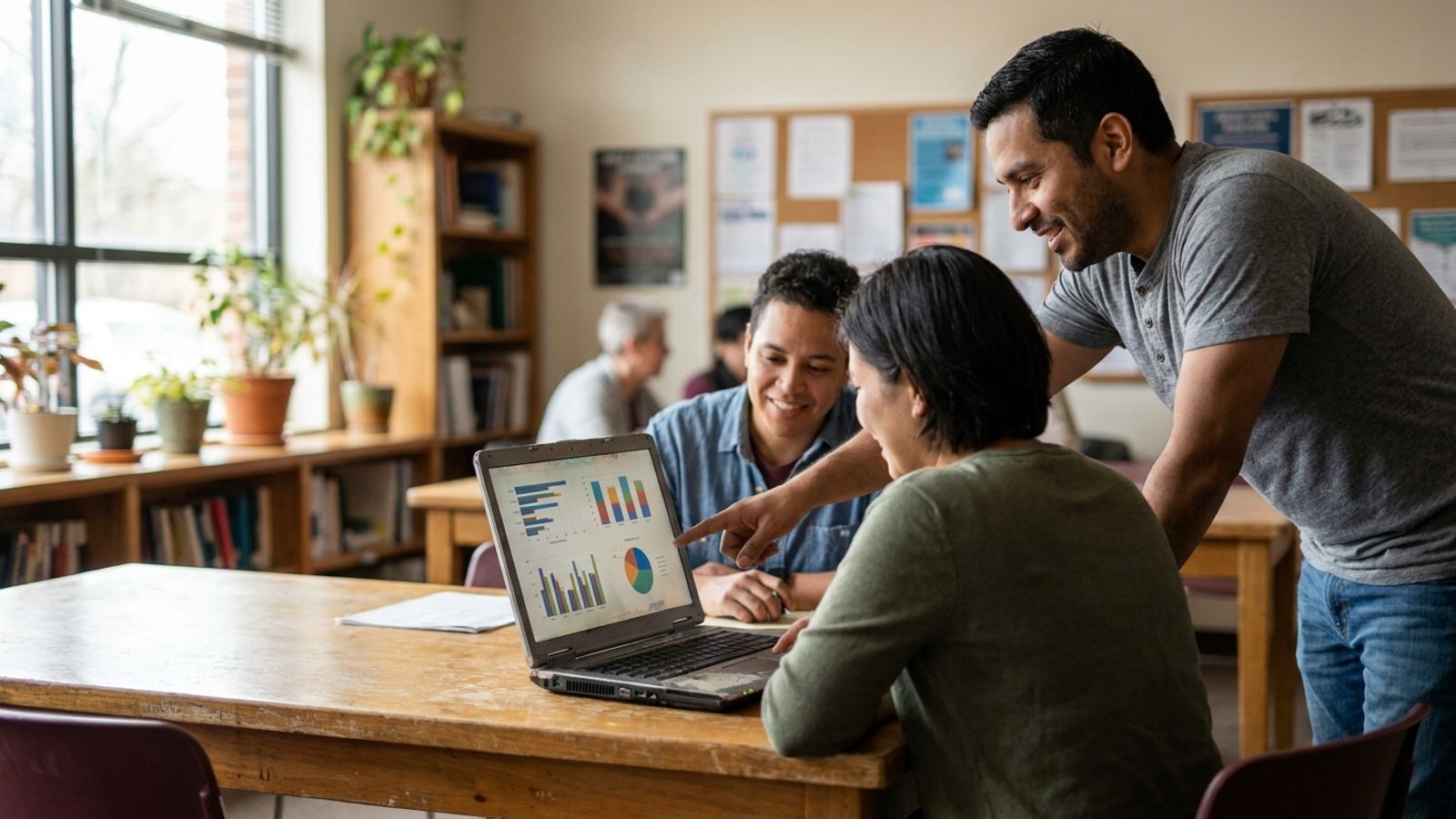 A nonprofit team reviewing charts and data on a laptop in a community office